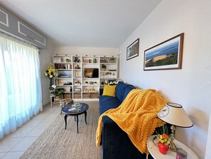 Een woonkamer met een bank, een salontafel, een boekenkast en een televisie.