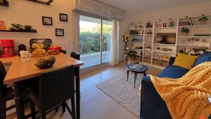 Ein Wohnzimmer mit Essbereich, einer Bücherwand und Blick ins Freie.