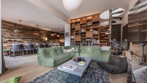 Ein modernes Wohnzimmer mit einem grünen Sofa, einem Couchtisch und einer Bücherwand voller Bücher.