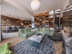 Ein modernes Wohnzimmer mit einem grünen Sofa, einem Couchtisch und einer Bücherwand voller Bücher.