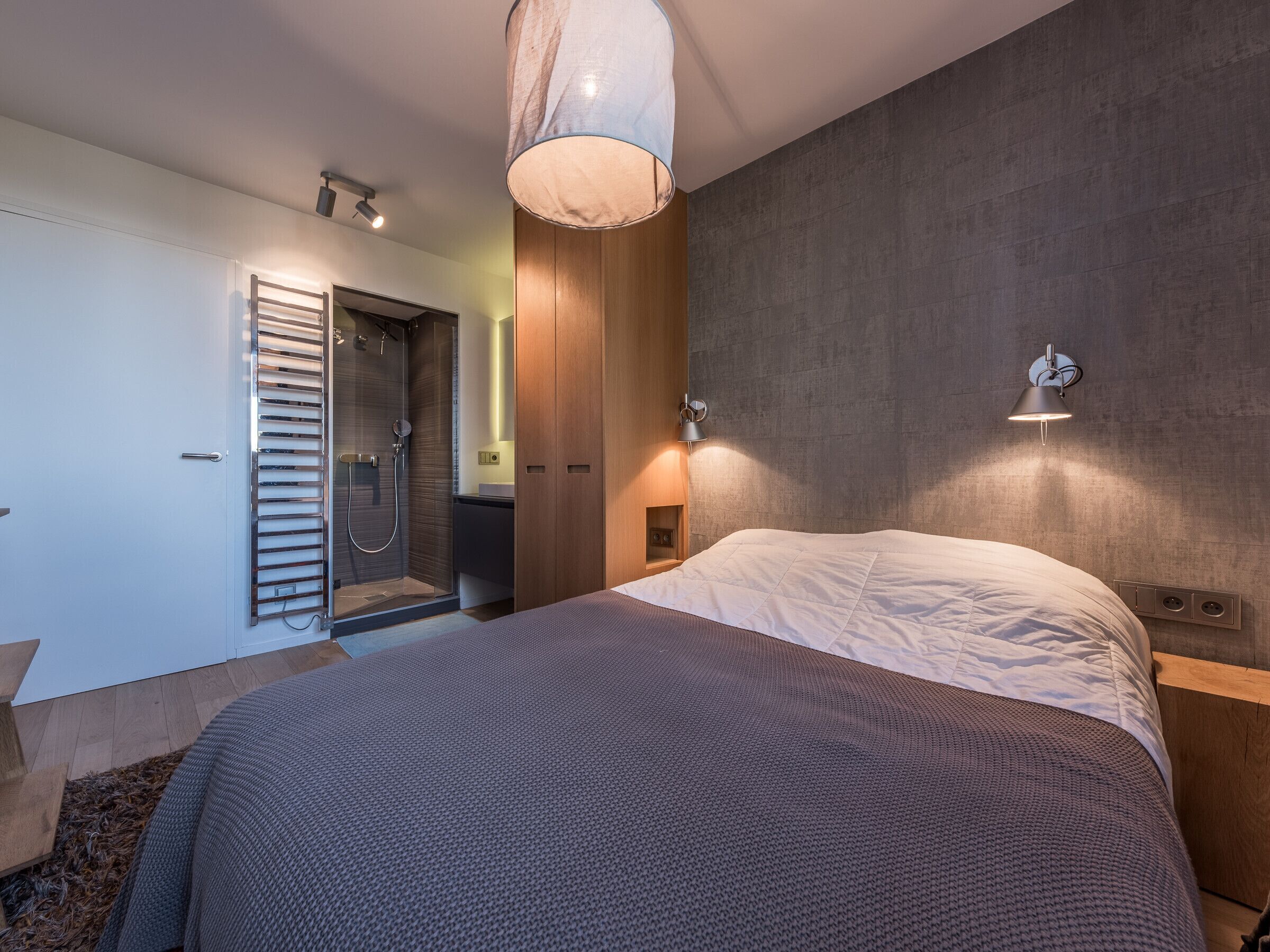 Un dormitorio moderno con una cama grande, un vestidor y una zona de ducha.