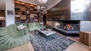 Ein modernes Wohnzimmer mit einem grünen Sofa, einem Glastisch und einem Kamin.