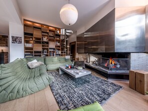 Ein modernes Wohnzimmer mit einem grünen Sofa, einem Glastisch und einem Kamin.