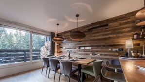 Eine moderne Küche mit einer Holzwand, einem großen Fenster und einem Essbereich mit Stühlen und einem Tisch.