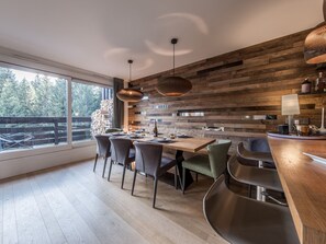 Eine moderne Küche mit einer Holzwand, einem großen Fenster und einem Essbereich mit Stühlen und einem Tisch.