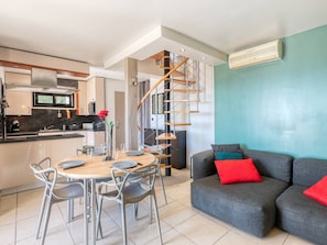A modern kitchen with a dining area, a staircase, and a living room with a sofa and cushions. - Superb villa with sea view, air conditioning, close to beach, parking, pets allowed (Le Lavandou)