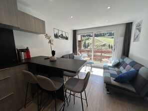Et moderne køkken med spiseplads, en sofa og udsigt til en vingård gennem store vinduer.