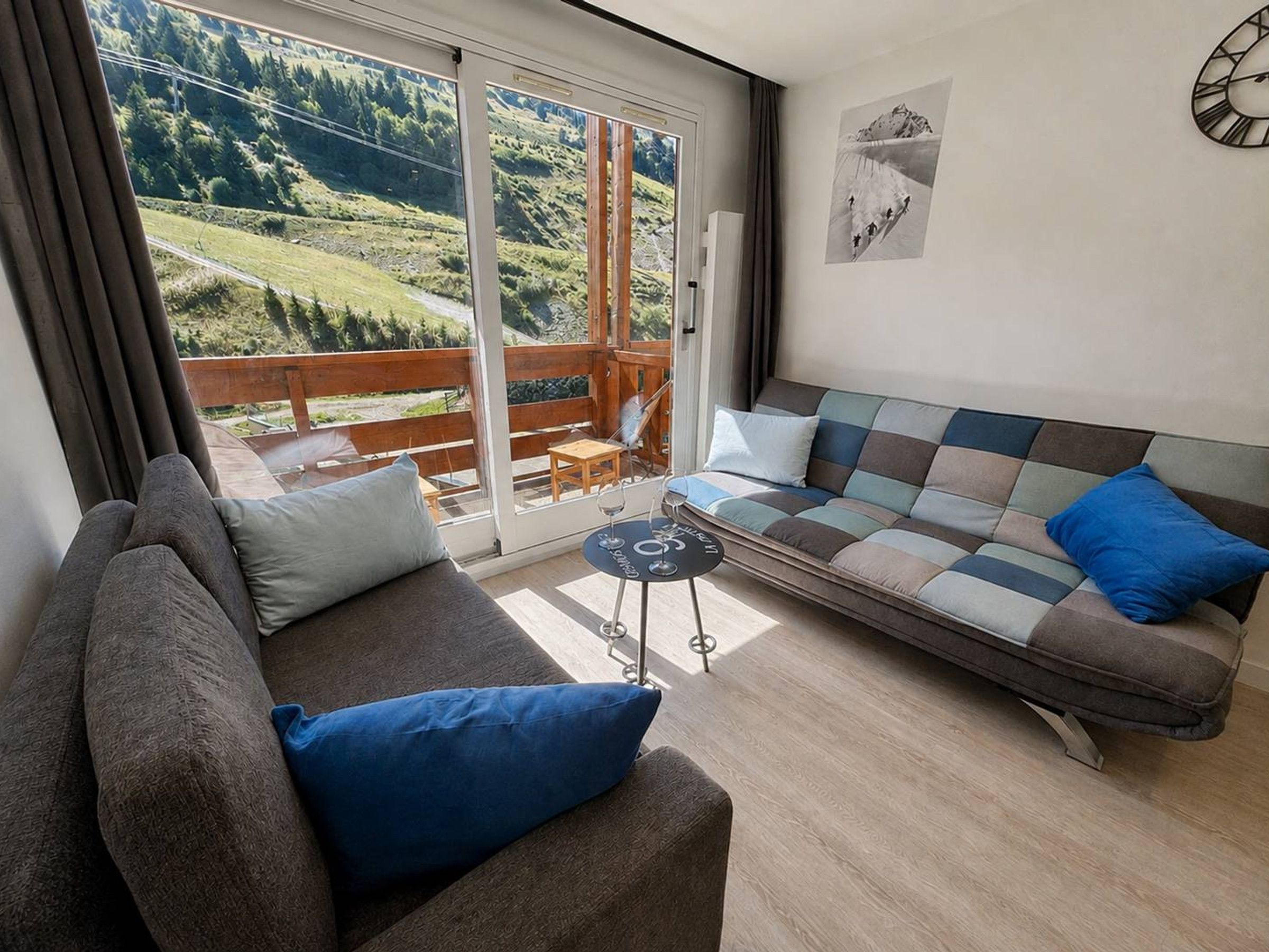 A modern living room with a sofa, a coffee table, and a view of a balcony with a wooden railing.