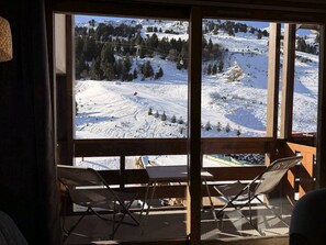 A room with a large window overlooking a snowy mountain landscape, including ski slopes and trees. - 3-Room Duplex in Méribel Mottaret, Family-Friendly, Ski-In/Ski-Out (Méribel)