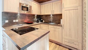 Eine moderne Küche mit Holzschränken, einem Einbauofen, einer Mikrowelle, einem Herd und einem Spülbecken.