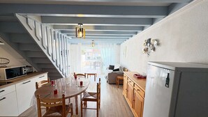 A modern kitchen with wooden cabinets, a dining table with chairs, and a staircase leading to an outdoor area. - Renovated 2023 house close to the ocean with terrace and WIFI (Biscarrosse Plage)