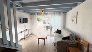 A modern living room with a sofa, a wooden table, and a TV on a stand. - Renovated 2023 house close to the ocean with terrace and WIFI (Biscarrosse Plage)