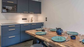Eine moderne Küche mit dunkelblauen Schränken, einem eingebauten Backofen und einem Holztisch, gedeckt mit blauen Tellern und Gläsern.
