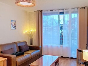 A living room with a brown leather sofa, a wooden coffee table, and a floor lamp. - Well-equipped studio at the foot of the slopes, central station (Les Deux Alpes)