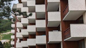 Un edifici de diversos pisos amb balcons, baranes de fusta i una filera de jardineres.