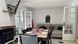 En matplats med ett bord dukat för fyra personer, omgiven av stolar, en soffa och en öppen spis.
