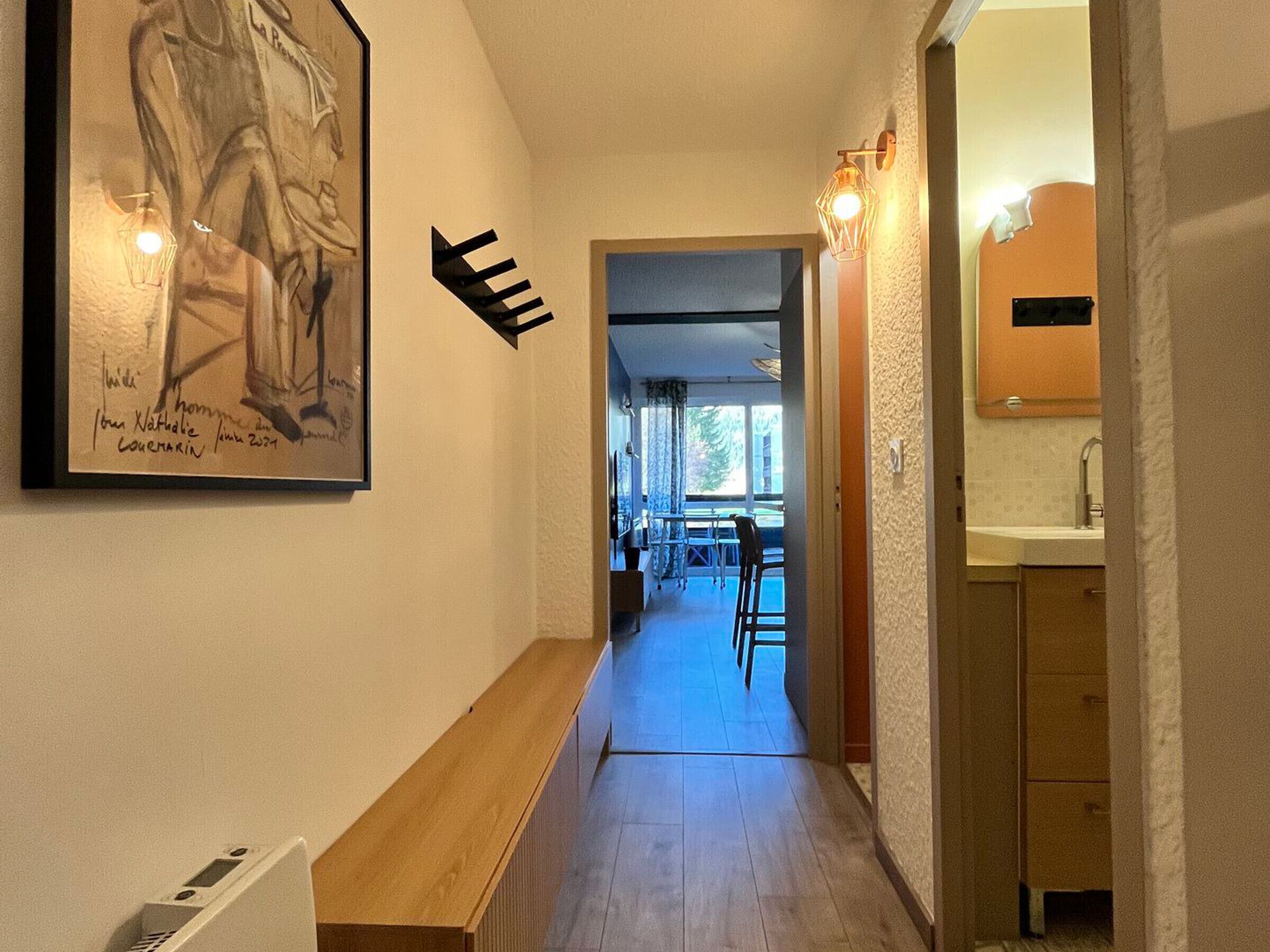 Un couloir avec un banc en bois, une œuvre d’art encadrée et un panneau de signalisation.
