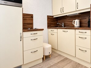 Eine Küche mit Holzausstattung, einem Wasserkocher und einem kleinen Hocker.