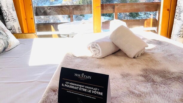 A cozy room with a bed, a fluffy white rug, and a sign in French. - Ski-in duplex for 4 with parking in Méribel (Méribel)
