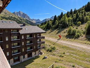 A modern building with multiple balconies, a dirt path, and a mountainous backdrop. - Ski-in duplex for 4 with parking in Méribel (Méribel)