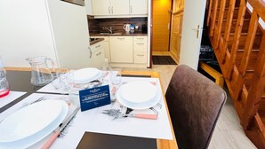 A dining area with a table set for four, a kitchen in the background, and a wooden staircase. - Ski-in duplex for 4 with parking in Méribel (Méribel)