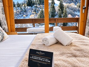 A hotel room with a bed, a wooden deck, and a view of a snowy landscape. - Ski-in duplex for 4 with parking in Méribel (Méribel)