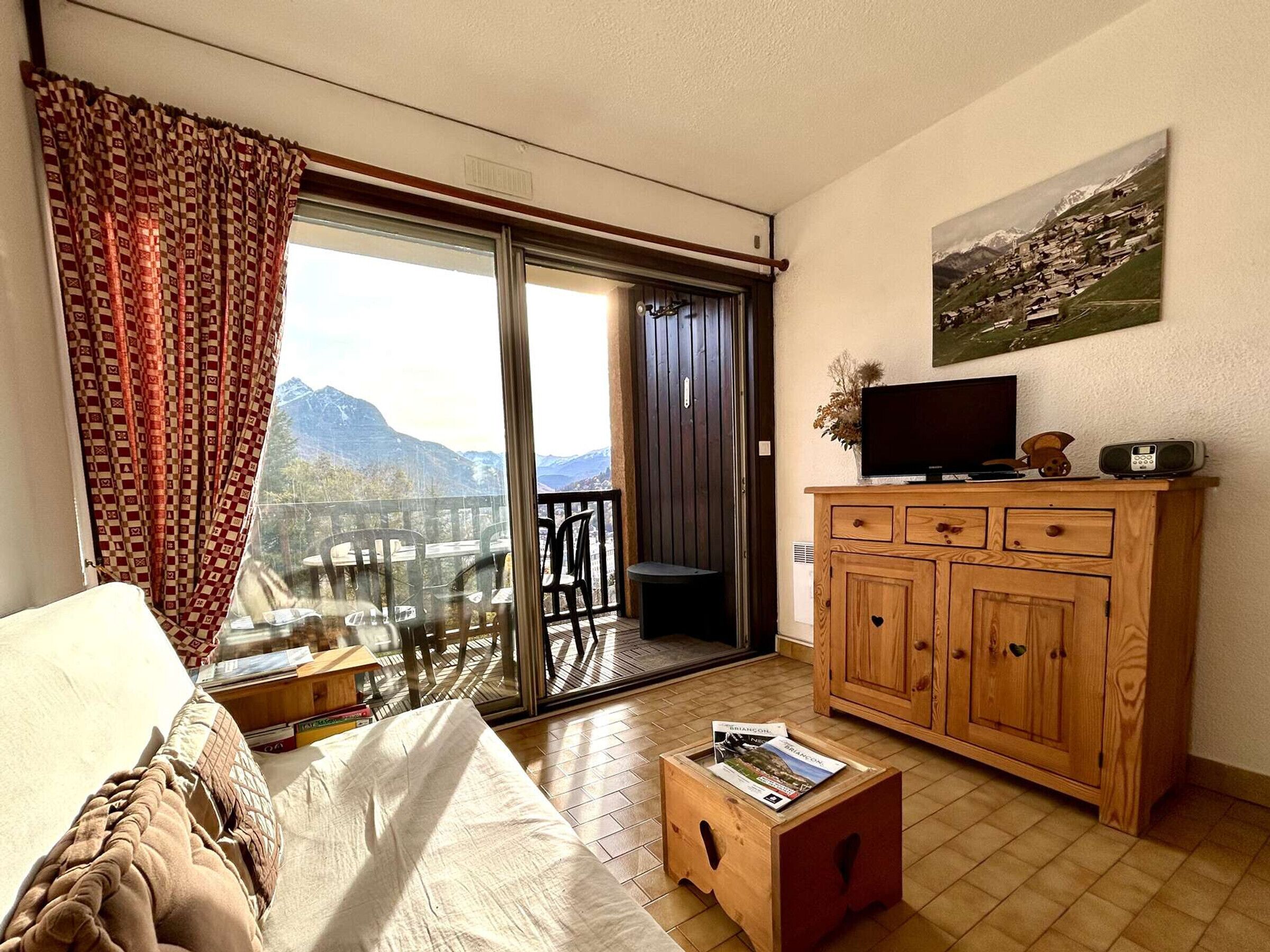 Une chambre avec un lit, une armoire en bois, une télévision et une vue sur les montagnes, visible par une porte coulissante.