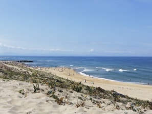 Ein Strand mit sandigem Ufer, Wellen und blauem Himmel.
