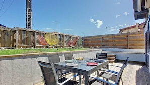 An outdoor patio with a table and chairs, a wooden fence, and a clear blue sky. - Villa in Vieux-Boucau for 10, near ocean, with terrace (Vieux-Boucau-les-Bains)