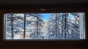 Een uitzicht op besneeuwde bomen en een heldere blauwe lucht.