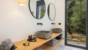Un baño moderno con dos lavamanos de piedra, un mueble de tocador de madera y un espejo grande.