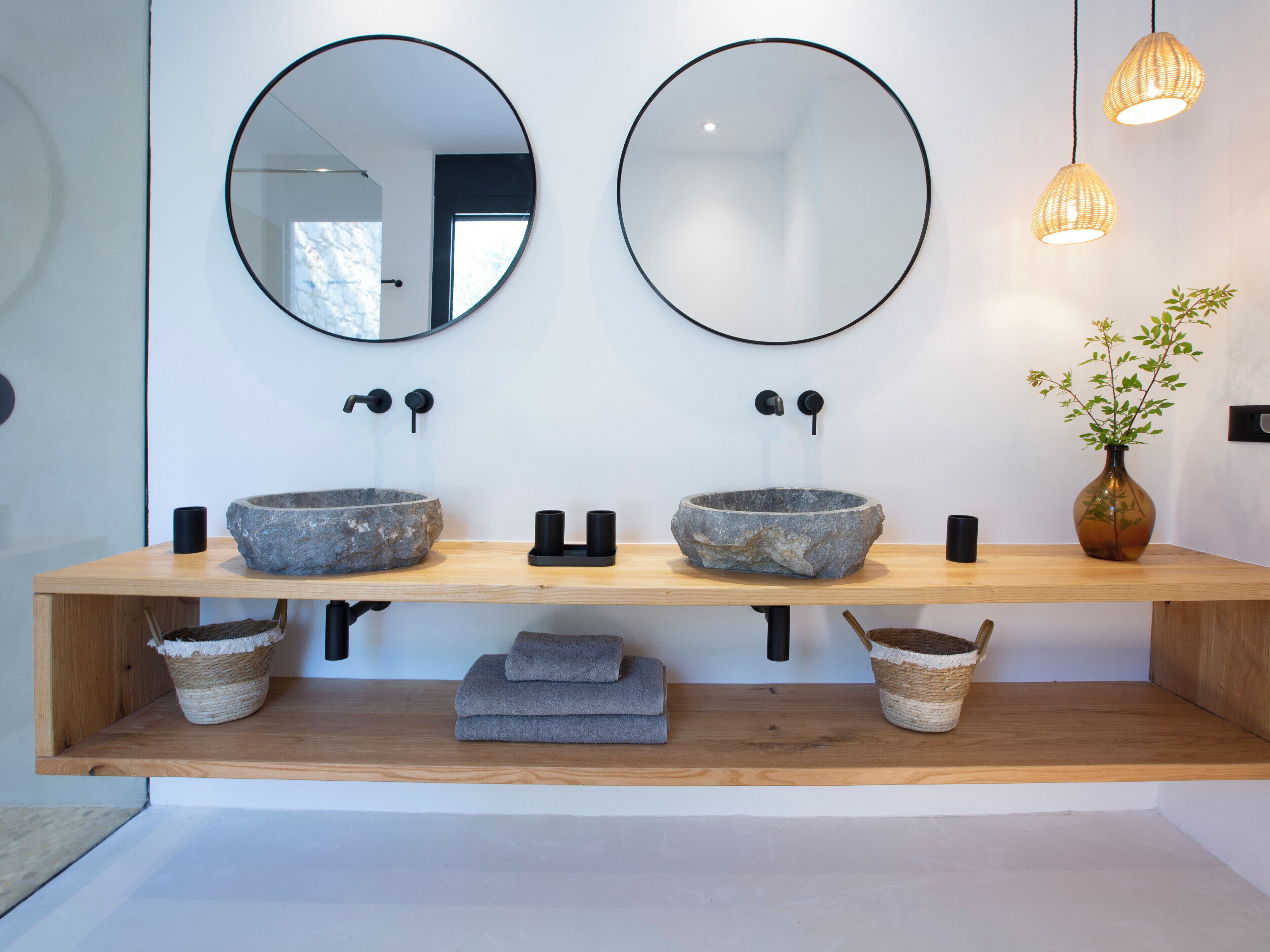 A bathroom with two stone sinks, a wooden vanity, and a potted plant.