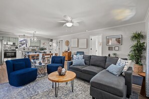 Ein modernes Wohnzimmer mit einem grauen Sofa, blauen Sesseln und einem Holztisch.
