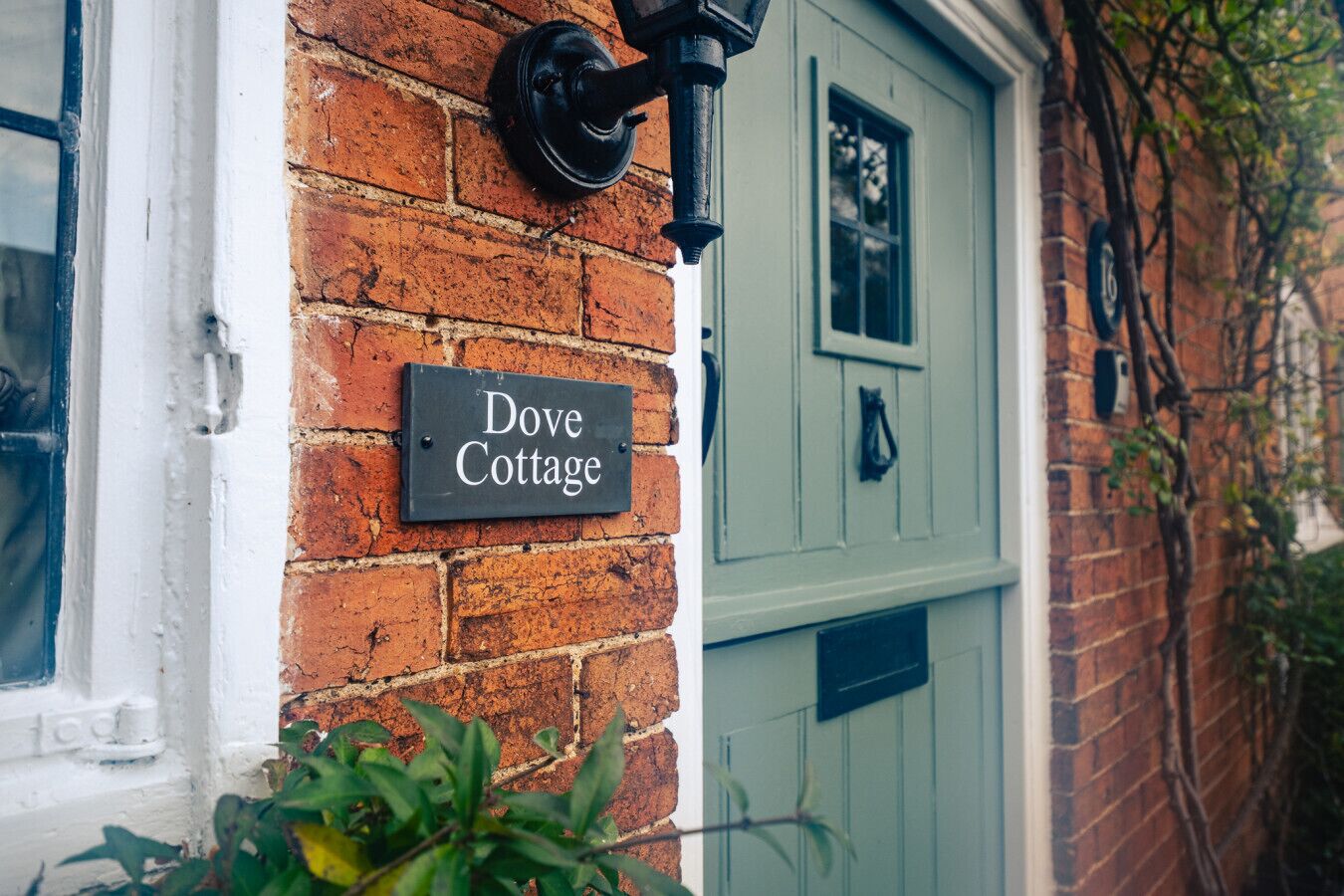 A brick wall with a black sign reading "Dove Cottage."
