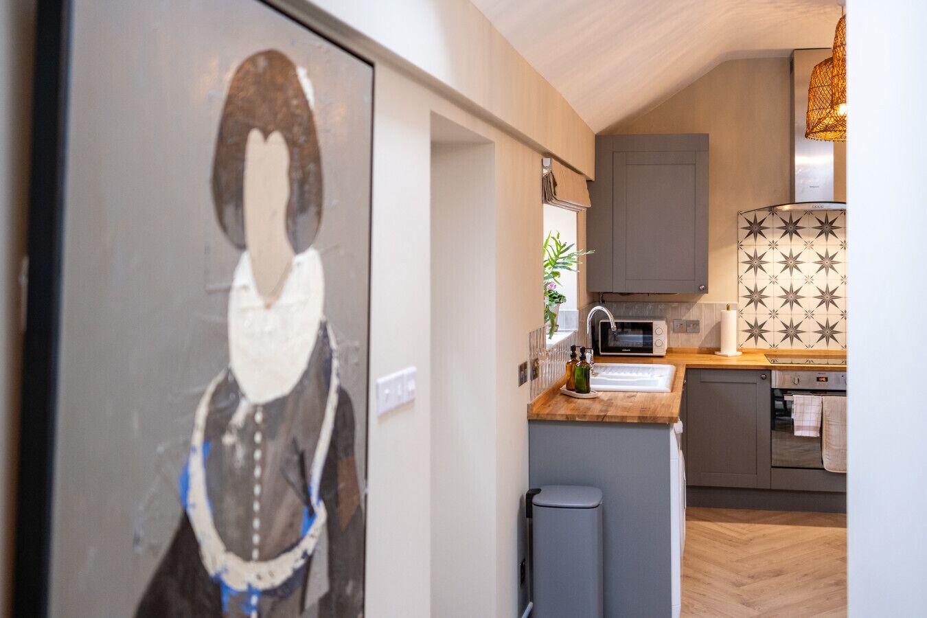 A modern kitchen with grey cabinets, a microwave, and a patterned backsplash.