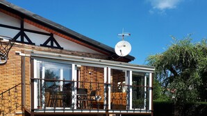 Une maison à deux étages dotée d’un balcon, d’une antenne parabolique et d’une façade en briques.