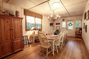 Ein Esszimmer mit Holztisch und -stühlen, einer Chandelüster und einem Schrank.