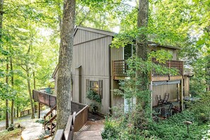 Ein Baumhaus mit Holzfassade, einer Holzterrasse und einem kleinen Balkon.