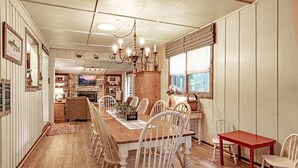 A dining area with a wooden table and chairs, a chandelier, and a view of the kitchen in the background. - Grandville at Rumbling Bald (Lake Lure)