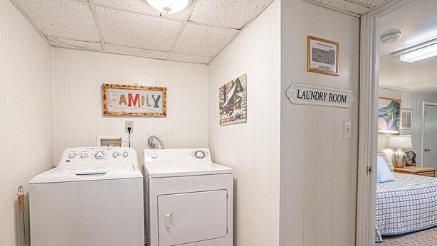 A laundry room with two washing machines, a family sign, and a painting on the wall. - Grandville at Rumbling Bald (Lake Lure)