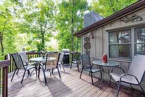 Eine Holzterrasse mit Gartenmöbeln, einem Grill und einem Steinofen.