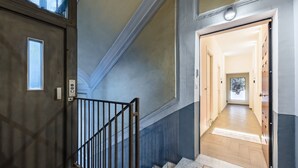 A staircase with a metal railing leading to a hallway with wooden flooring and a door at the end. - Solaris Suites  (Naples)