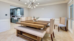 A dining area with a wooden table, bench seating, and a chandelier. - Heated Pool, Hot Tub, Game Room: Houston Group Gem (Houston)