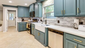 A kitchen with teal cabinetry, a stone backsplash, and a dishwasher. - Heated Pool, Hot Tub, Game Room: Houston Group Gem (Houston)