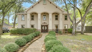 A two-story house with a symmetrical facade, a central entrance with a double door, and a small porch area. - Heated Pool, Hot Tub, Game Room: Houston Group Gem (Houston)