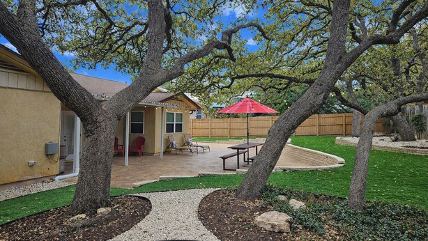 A backyard with a patio, a wooden fence, and a red umbrella. - Work, Explore & Unwind: Convenient San Antonio Gem (San Antonio)