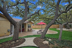 A backyard with a patio, a wooden fence, and a red umbrella. - Work, Explore & Unwind: Convenient San Antonio Gem (San Antonio)
