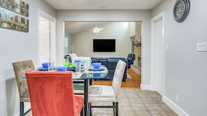 A dining area with a glass table, chairs, and a ceiling fan. There is a TV mounted on the wall and a door leading to another room. - Work, Explore & Unwind: Convenient San Antonio Gem (San Antonio)
