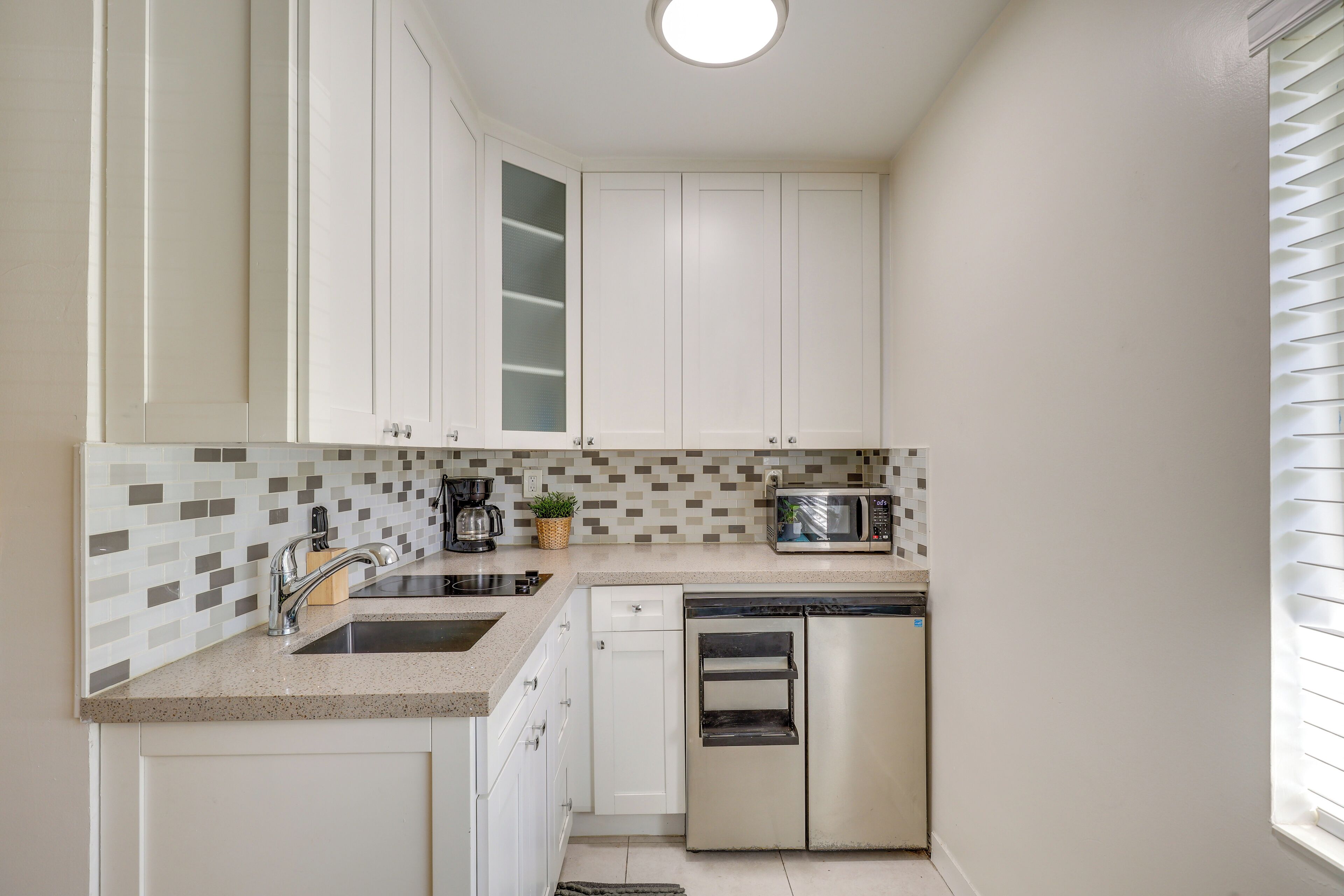 A modern kitchen with white cabinets, a microwave, a dishwasher, and a sink.