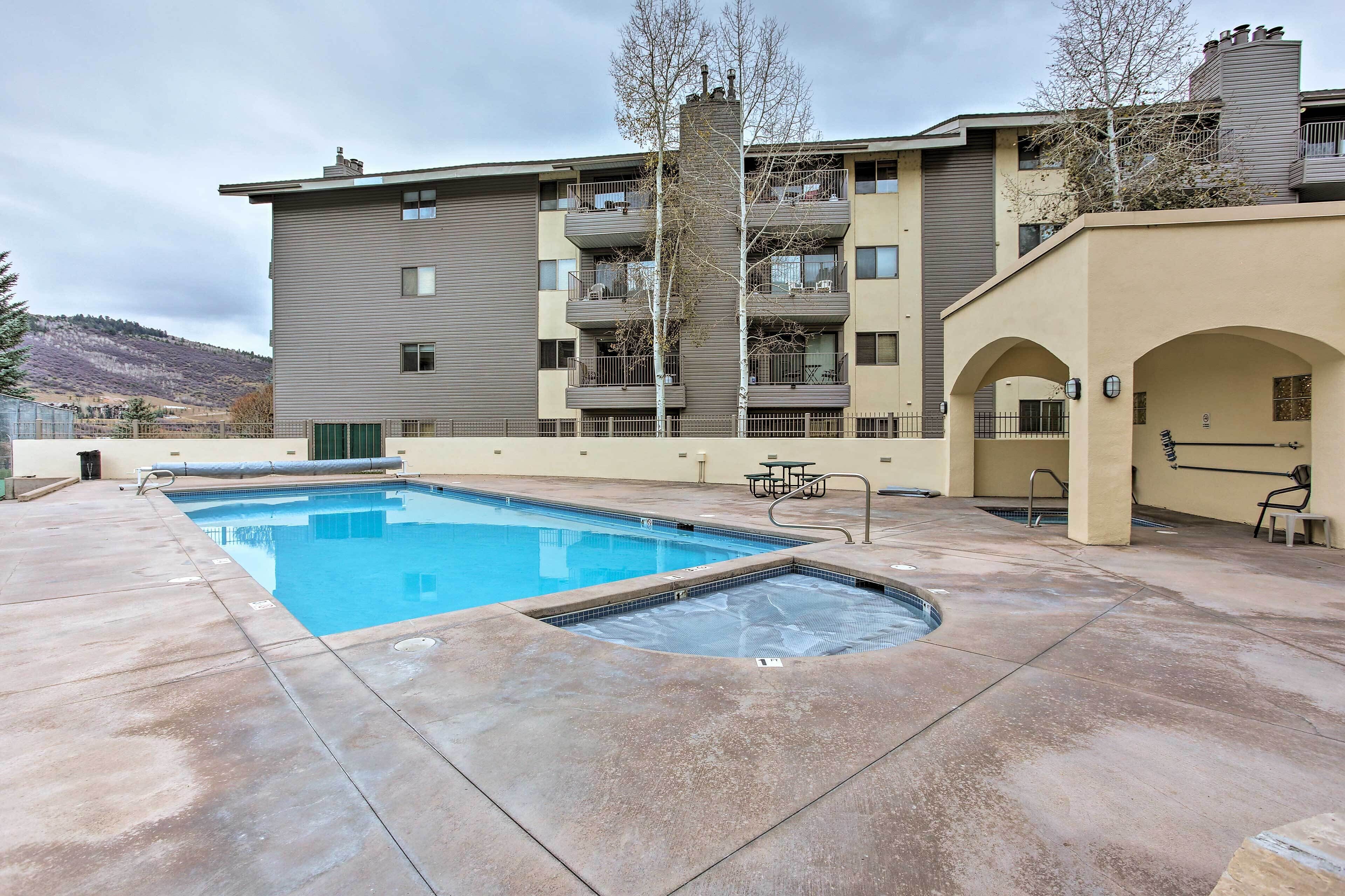 Um edifício de apartamentos moderno com piscina, área de estar ao ar livre e vista para as montanhas.